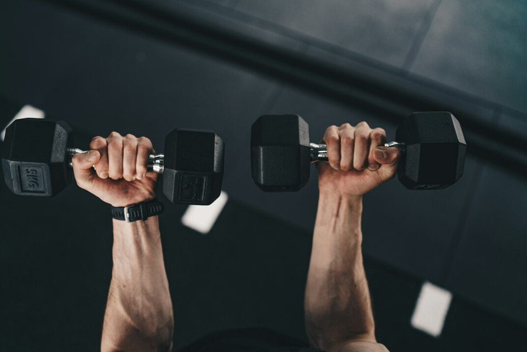 Athlete training with dumbbells in a bright gym